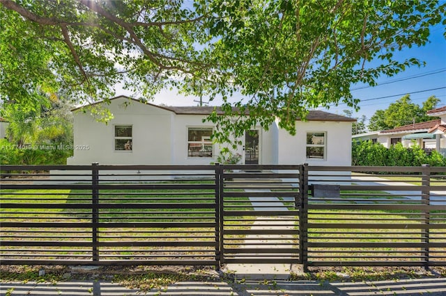 view of front of property featuring stucco siding, a fenced front yard, and a front yard