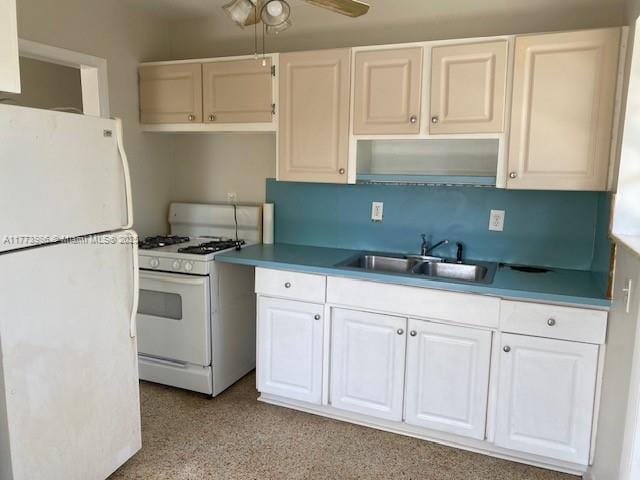 kitchen with white appliances, white cabinetry, a sink, and a ceiling fan