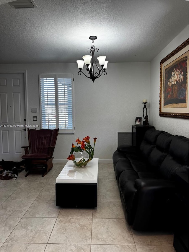 living area featuring a textured ceiling, baseboards, visible vents, light tile patterned flooring, and a chandelier