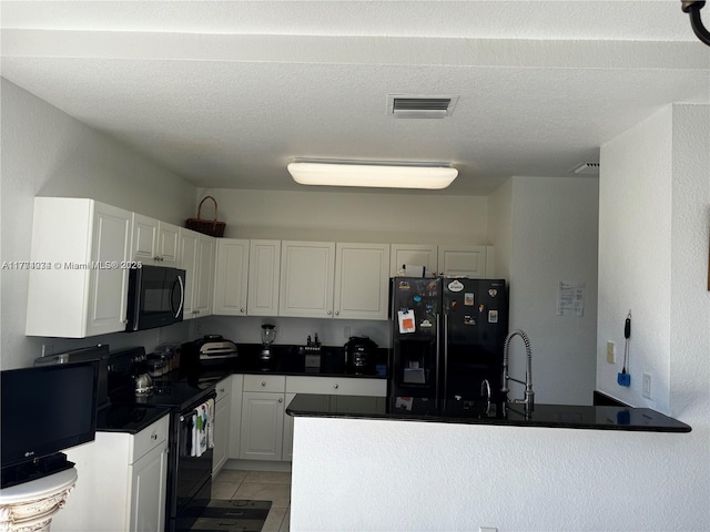 kitchen with a peninsula, dark countertops, white cabinets, visible vents, and black appliances