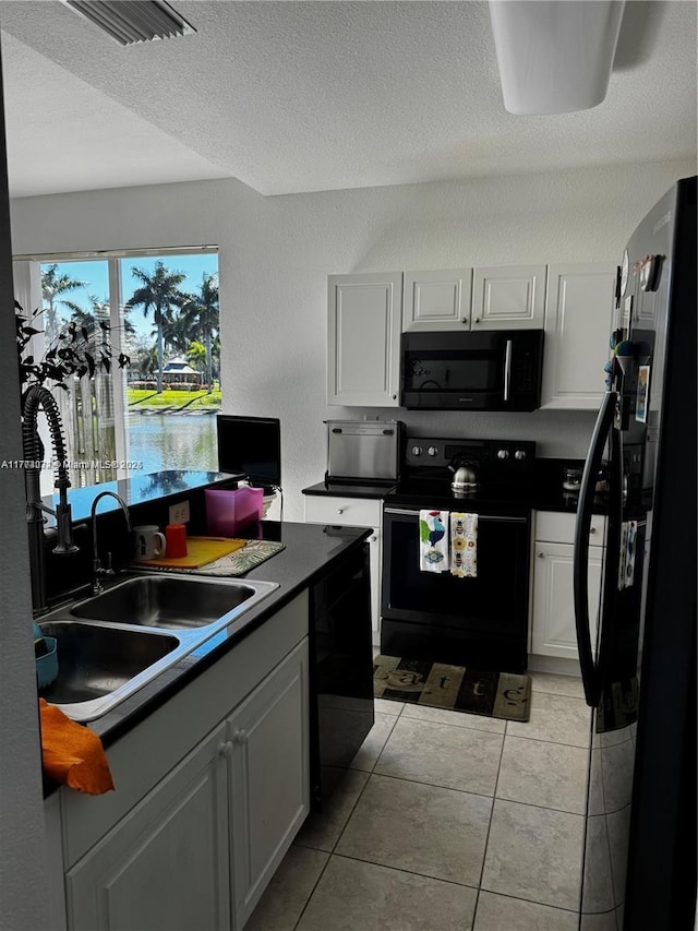 kitchen featuring a textured ceiling, light tile patterned floors, visible vents, a sink, and black appliances