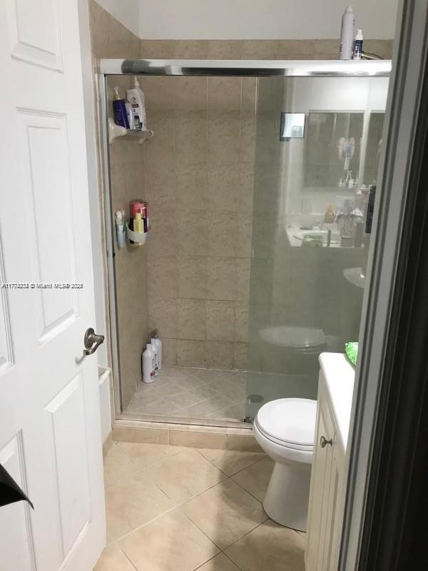full bath with toilet, tile patterned flooring, vanity, and a stall shower