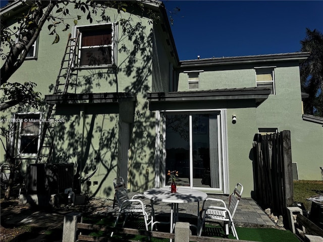 rear view of house featuring a patio area and stucco siding