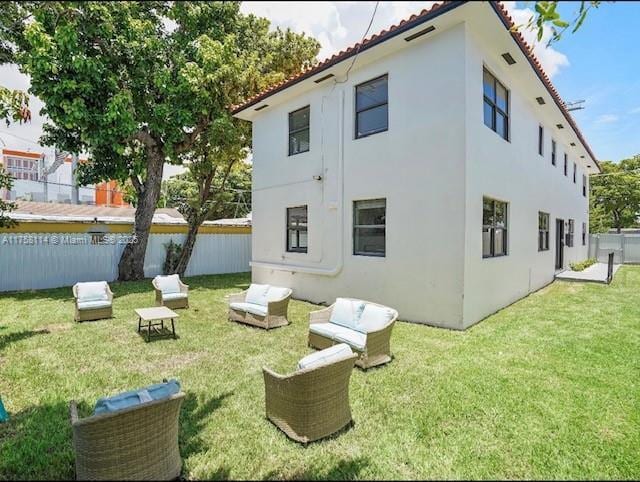 back of house featuring a tile roof, stucco siding, fence, and a yard