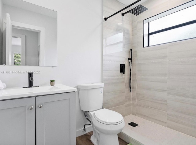 full bath with toilet, tiled shower, and vanity