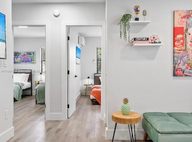 hall featuring a wall mounted air conditioner, baseboards, and wood finished floors