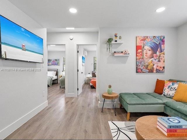 living area with baseboards, wood finished floors, and recessed lighting