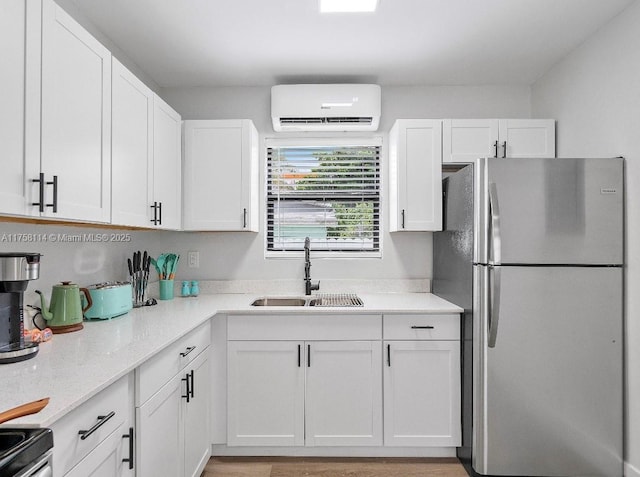 kitchen featuring range with electric cooktop, white cabinetry, a sink, an AC wall unit, and freestanding refrigerator