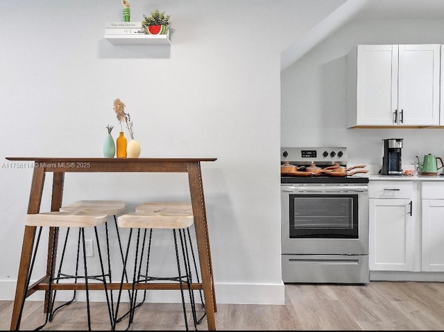kitchen featuring white cabinets, light countertops, stainless steel electric range oven, and light wood finished floors