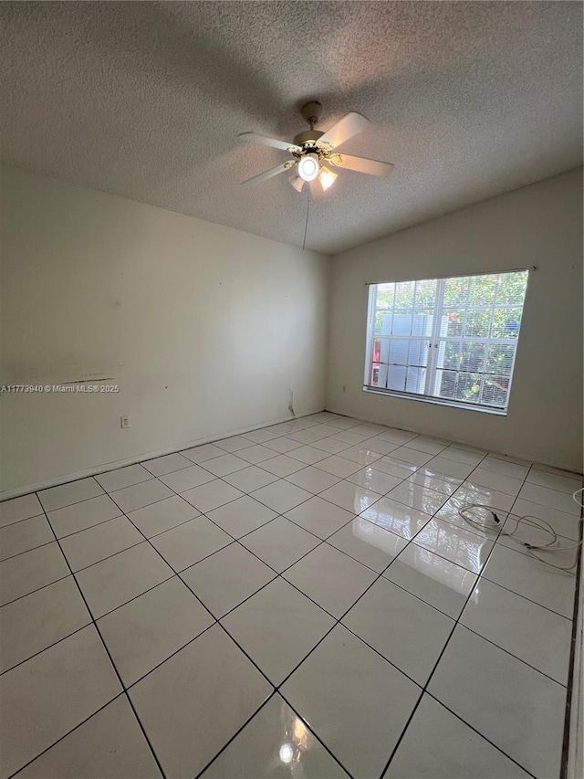 unfurnished room featuring a textured ceiling, ceiling fan, and light tile patterned floors