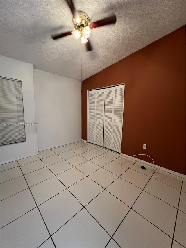empty room with light tile patterned flooring, a textured ceiling, lofted ceiling, and ceiling fan