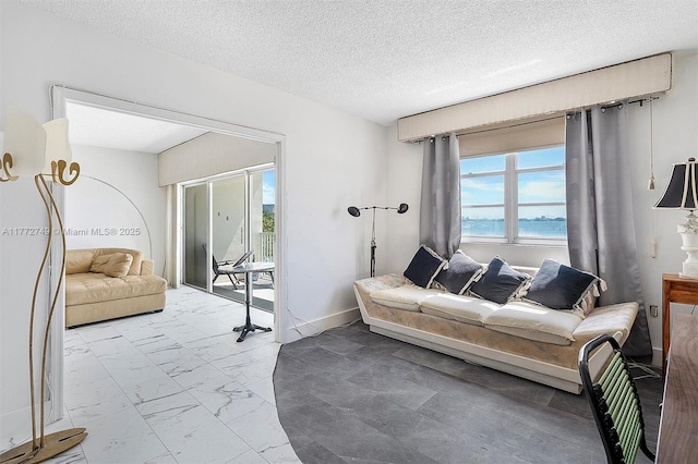300 Bayview Dr Unit 308, Sunny Isles Beach, FL 33160 - living area featuring marble finish floors, healthy amount of natural light, a textured ceiling, and a water view