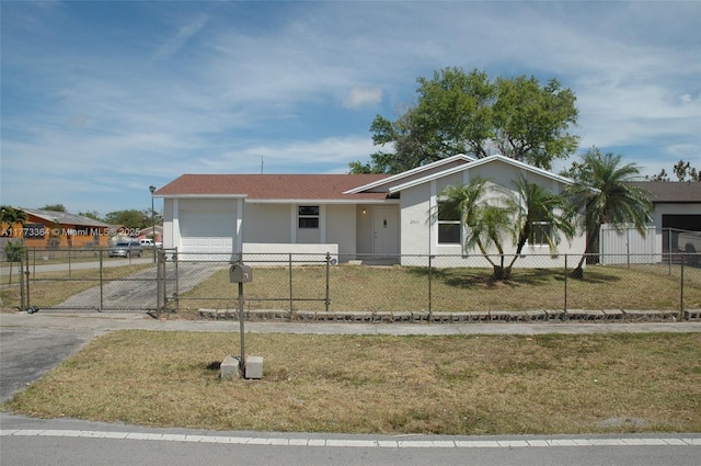 view of front of house with a fenced front yard, driveway, a garage, and a front lawn