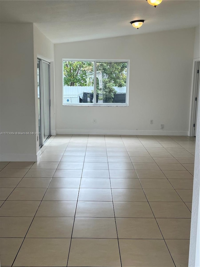 empty room with light tile patterned floors and baseboards