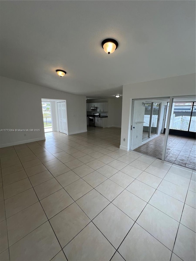 empty room with light tile patterned flooring and baseboards