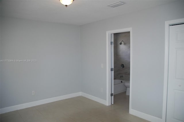 empty room featuring baseboards, visible vents, and light tile patterned floors