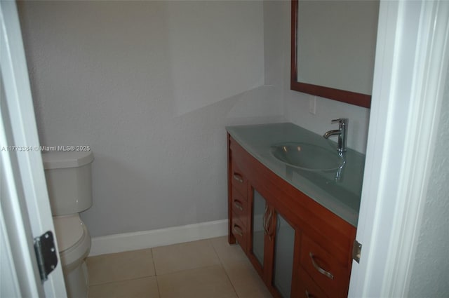 half bathroom with baseboards, toilet, tile patterned flooring, and vanity