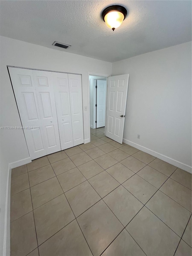 unfurnished bedroom featuring baseboards, visible vents, a closet, and a textured ceiling