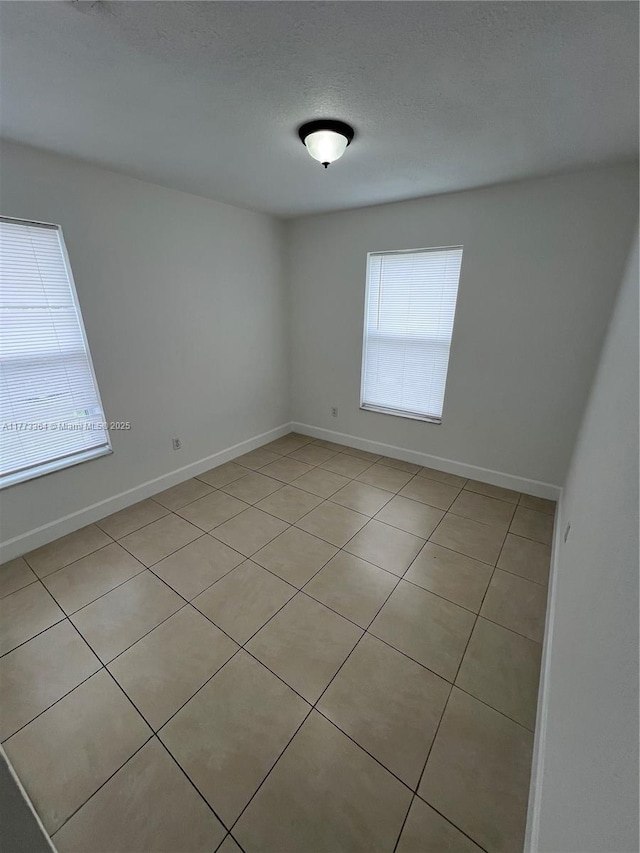 unfurnished room with baseboards and a textured ceiling