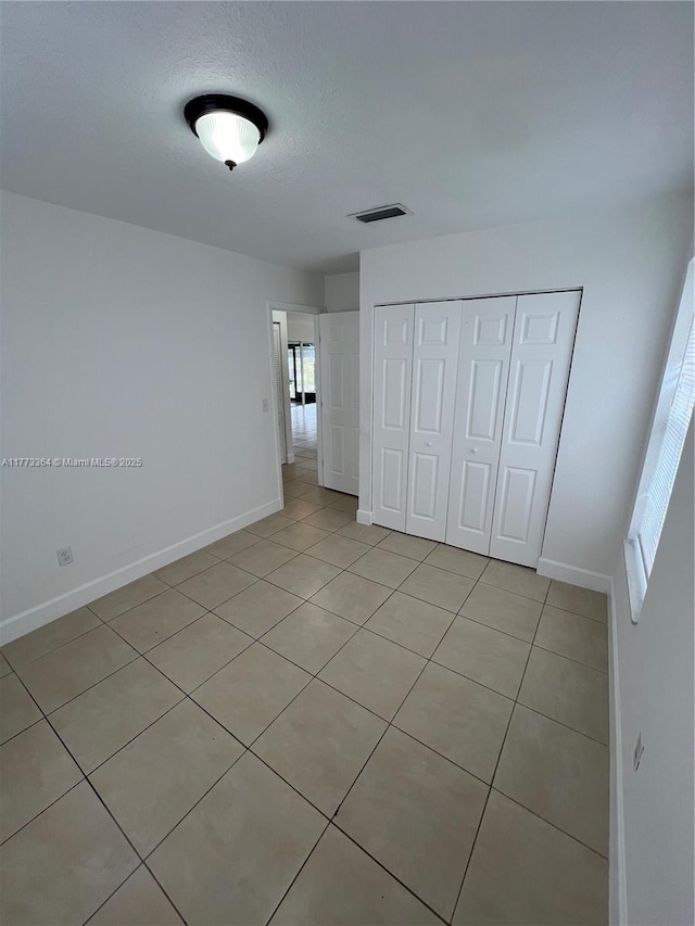 unfurnished bedroom featuring a closet, baseboards, a textured ceiling, and visible vents