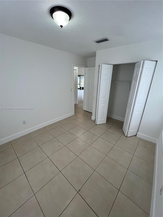 unfurnished bedroom with a closet, baseboards, a textured ceiling, and visible vents