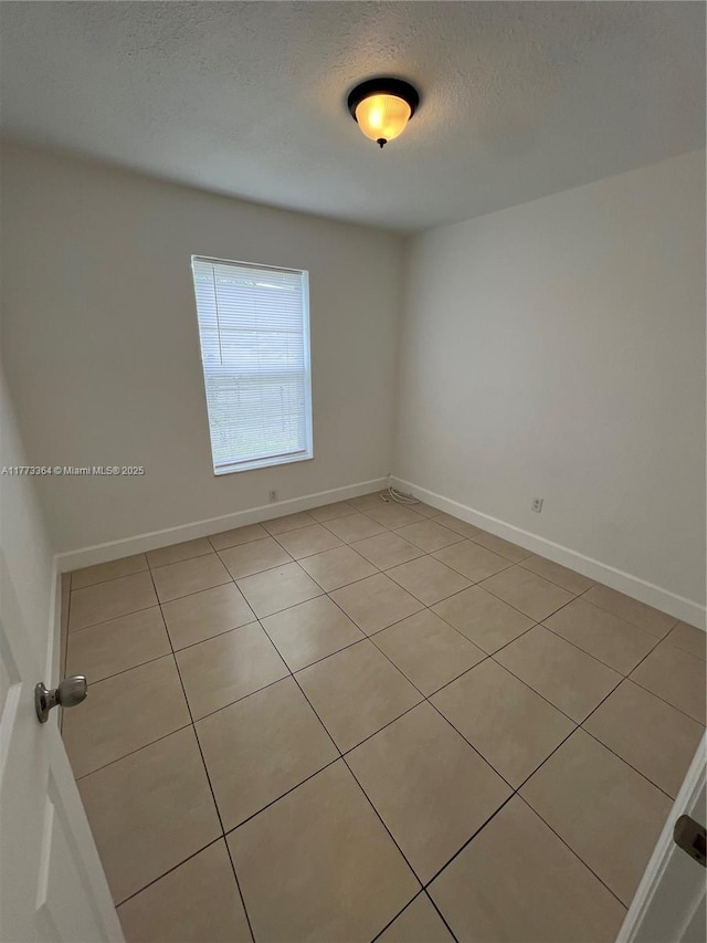 spare room featuring baseboards and a textured ceiling