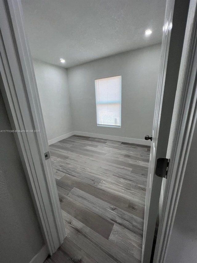 spare room featuring recessed lighting, baseboards, and wood finished floors