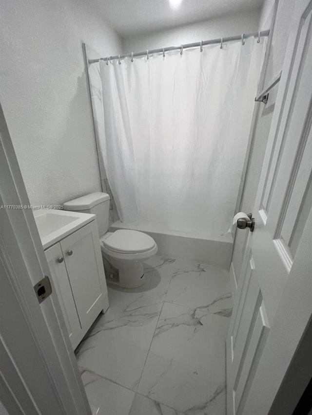 bathroom featuring marble finish floor, toilet, vanity, and shower / bath combo