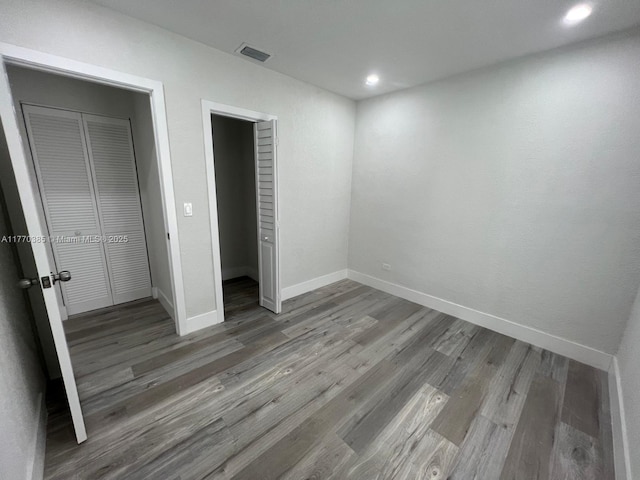 unfurnished bedroom with visible vents, a closet, baseboards, and wood finished floors