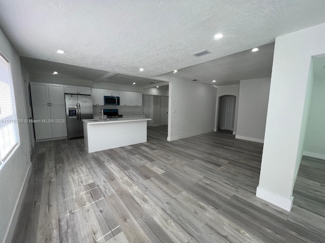 kitchen with visible vents, baseboards, stainless steel appliances, light wood-type flooring, and open floor plan