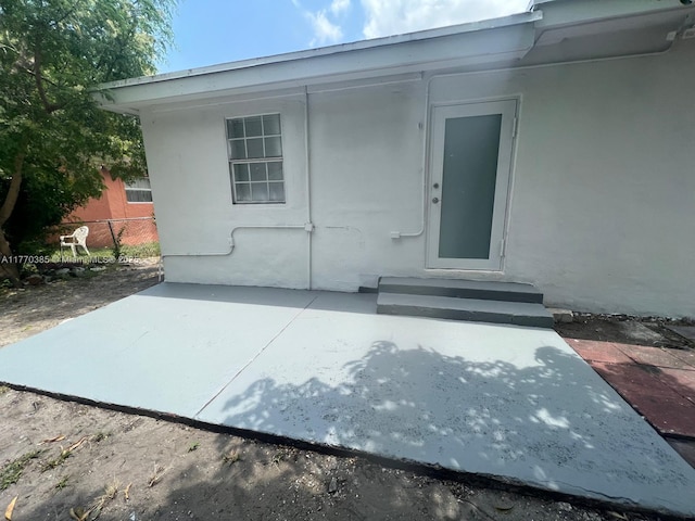 view of exterior entry featuring stucco siding and fence