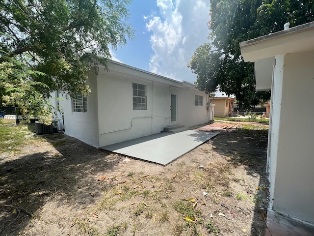 back of house with cooling unit, fence, stucco siding, and a patio area