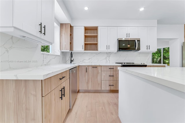 kitchen featuring decorative backsplash, light stone countertops, appliances with stainless steel finishes, open shelves, and light wood-style floors