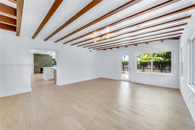 unfurnished room featuring beamed ceiling and light wood-type flooring