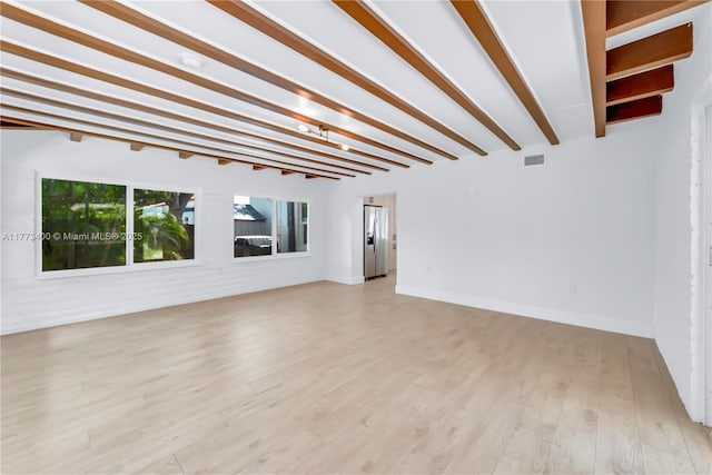 unfurnished living room featuring light wood-type flooring, baseboards, visible vents, and beamed ceiling