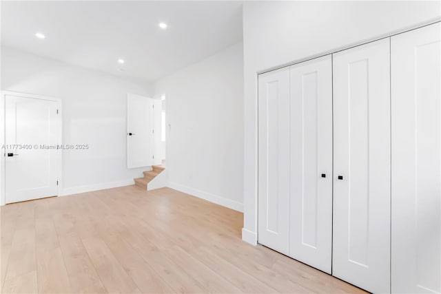 unfurnished bedroom with light wood-style flooring, a closet, baseboards, and recessed lighting