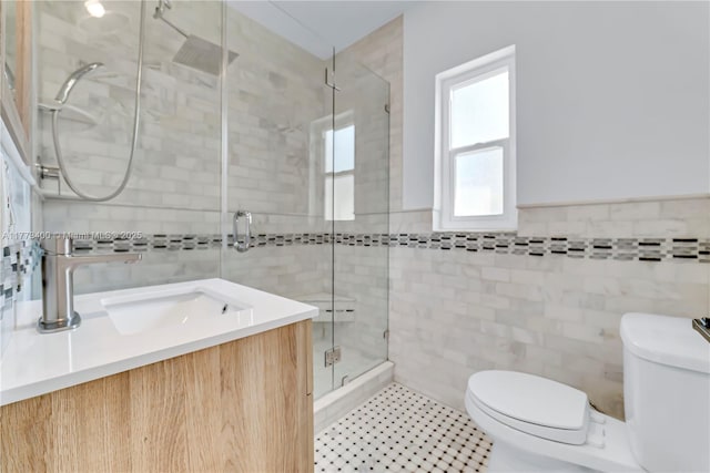 full bathroom featuring a stall shower, toilet, vanity, and tile walls