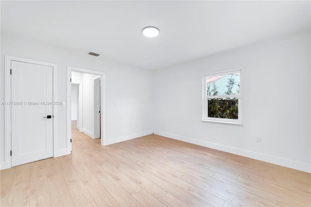 unfurnished room featuring baseboards, visible vents, and light wood-style flooring