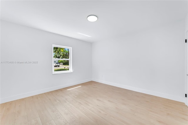 empty room with baseboards and light wood-type flooring
