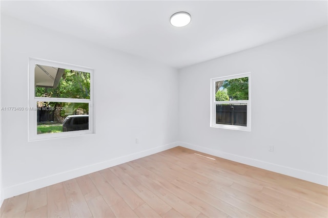 spare room featuring baseboards and light wood-type flooring