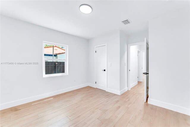 empty room featuring light wood finished floors, baseboards, and visible vents