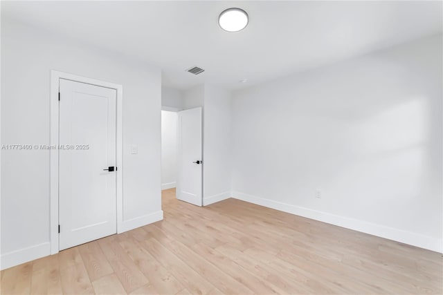 empty room featuring baseboards, light wood-style floors, and visible vents
