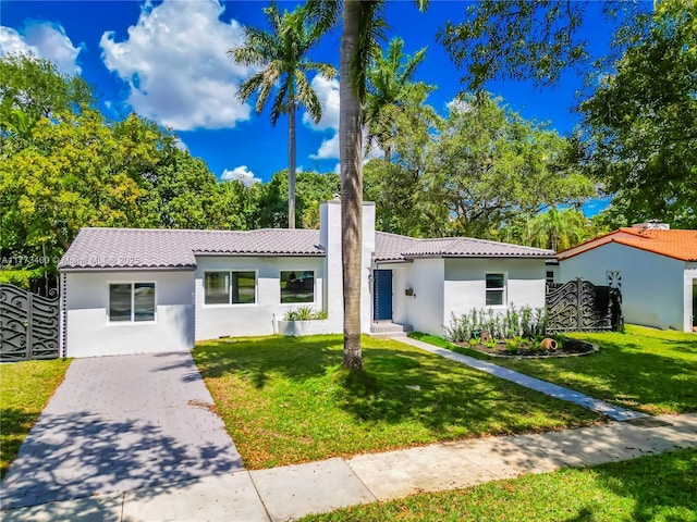 mediterranean / spanish-style house featuring a front lawn, fence, stucco siding, and a tiled roof