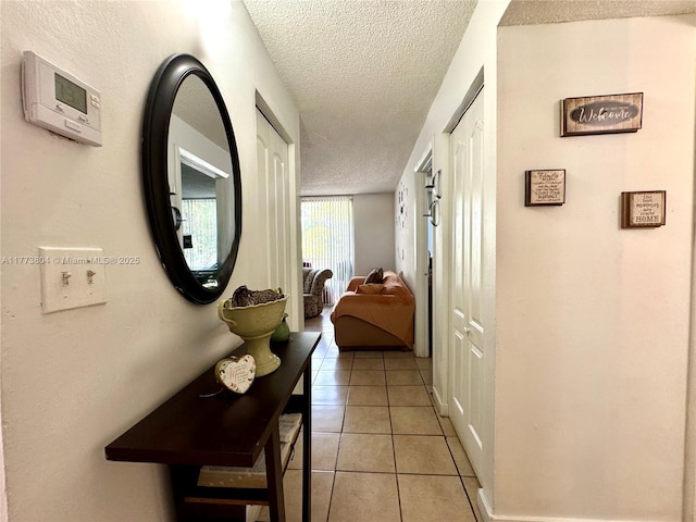 hall with light tile patterned flooring and a textured ceiling