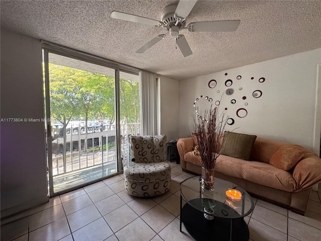 living area with expansive windows, a textured ceiling, ceiling fan, and light tile patterned floors