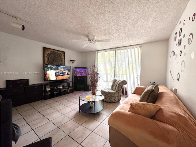 living room with a ceiling fan, light tile patterned flooring, expansive windows, and a textured ceiling