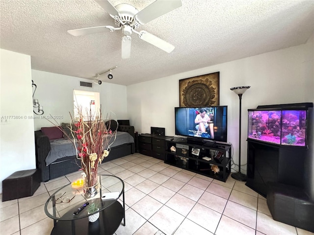 living area with a textured ceiling, a ceiling fan, visible vents, and light tile patterned floors