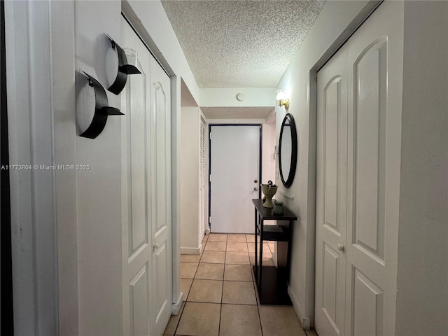 hall with light tile patterned floors and a textured ceiling