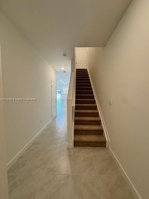 stairs featuring baseboards and tile patterned flooring