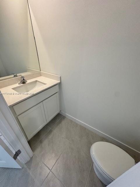 bathroom with baseboards, toilet, tile patterned flooring, and vanity